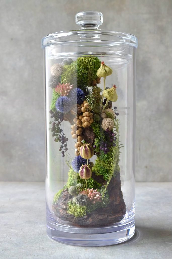 叢屋のドライフラワーを用いて、鬱蒼とした植物群が広がる深い森の一角を切り取ったようなボタニカルオブジェ。苔や木皮を組み合わせ、植物が群生する森の景色をジオラマのように立体的に表現しました。