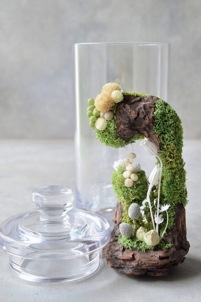 叢屋のドライフラワーを用いて、鬱蒼とした植物群が広がる深い森の一角を切り取ったようなボタニカルオブジェ。苔や木皮を組み合わせ、植物が群生する森の景色をジオラマのように立体的に表現しました。