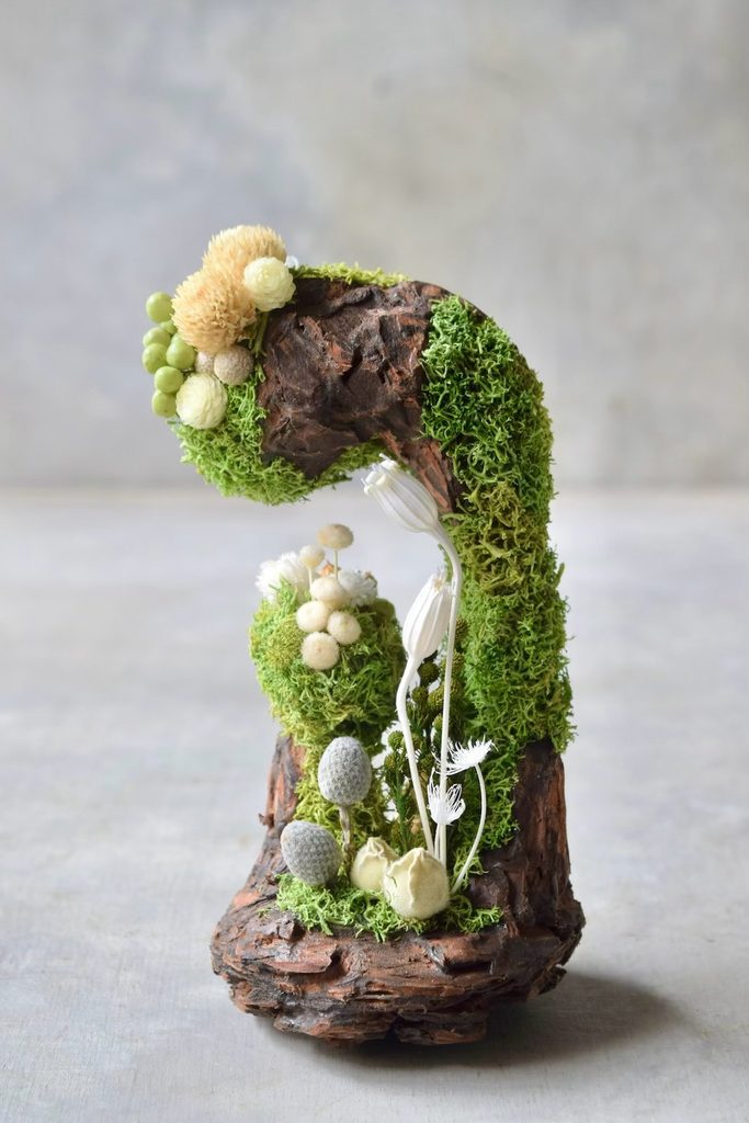 叢屋のドライフラワーを用いて、鬱蒼とした植物群が広がる深い森の一角を切り取ったようなボタニカルオブジェ。苔や木皮を組み合わせ、植物が群生する森の景色をジオラマのように立体的に表現しました。