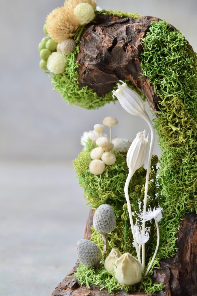 叢屋のドライフラワーを用いて、鬱蒼とした植物群が広がる深い森の一角を切り取ったようなボタニカルオブジェ。苔や木皮を組み合わせ、植物が群生する森の景色をジオラマのように立体的に表現しました。