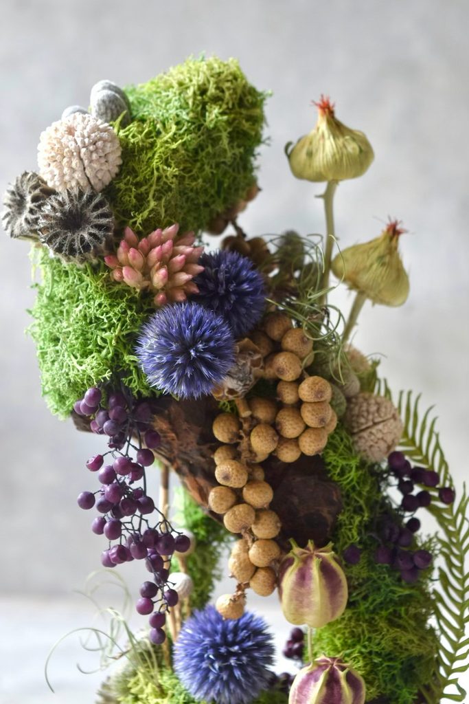 叢屋のドライフラワーを用いて、鬱蒼とした植物群が広がる深い森の一角を切り取ったようなボタニカルオブジェ。苔や木皮を組み合わせ、植物が群生する森の景色をジオラマのように立体的に表現しました。