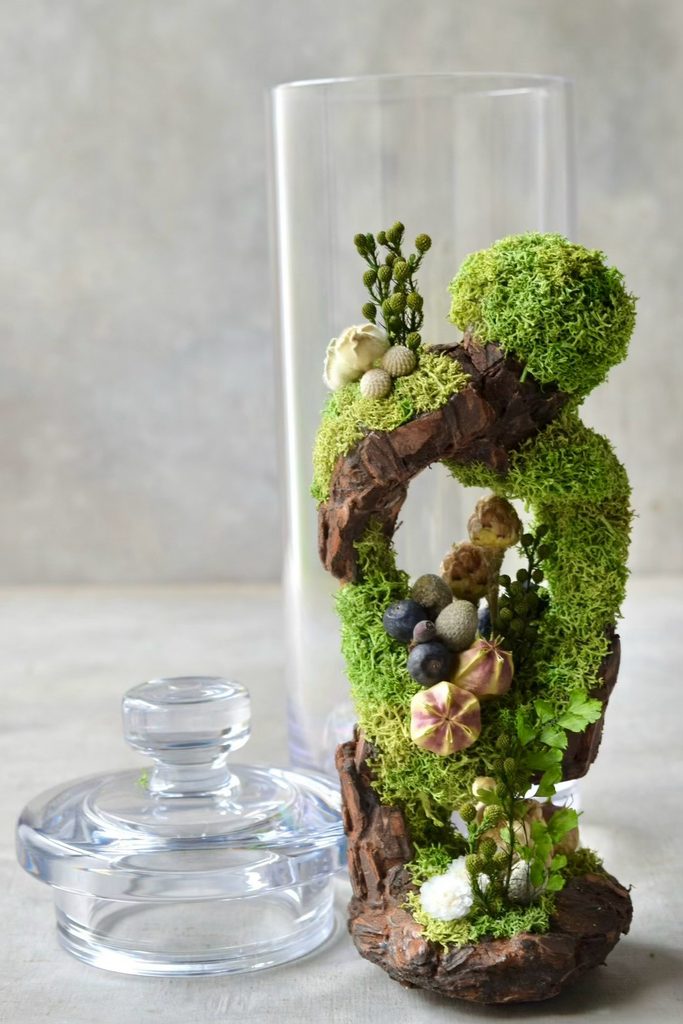 叢屋のドライフラワーを用いて、鬱蒼とした植物群が広がる深い森の一角を切り取ったようなボタニカルオブジェ。苔や木皮を組み合わせ、植物が群生する森の景色をジオラマのように立体的に表現しました。