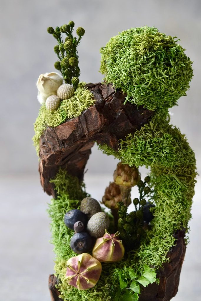 叢屋のドライフラワーを用いて、鬱蒼とした植物群が広がる深い森の一角を切り取ったようなボタニカルオブジェ。苔や木皮を組み合わせ、植物が群生する森の景色をジオラマのように立体的に表現しました。