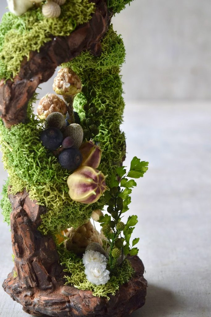 叢屋のドライフラワーを用いて、鬱蒼とした植物群が広がる深い森の一角を切り取ったようなボタニカルオブジェ。苔や木皮を組み合わせ、植物が群生する森の景色をジオラマのように立体的に表現しました。